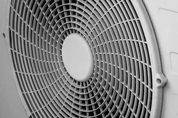 Close-up of a circular fan grille with parallel lines, likely part of an air conditioning unit.