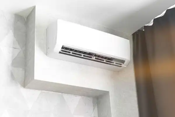 Wall-mounted air conditioning unit installed in a corner, with a curtain partially visible to the right.