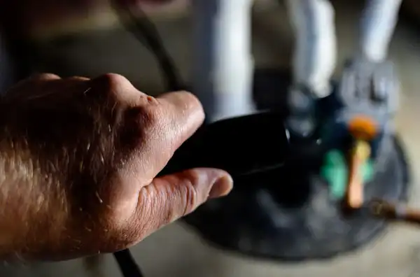 A person’s hand holding a television remote control, pointing toward a blurry screen.
